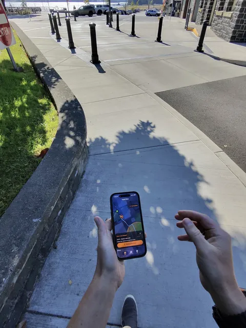 A visitor following Haunt Shot walking directions on an iPhone beside a sidewalk in St. Helens.